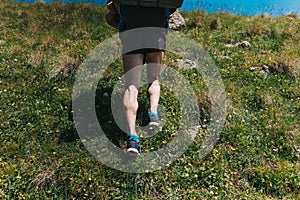 Muscular calves of a young athlete running with backpack up a mo