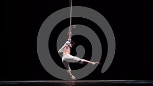 Muscular circus artist perform on the aerial straps on black background. Concept of originality, creativity and