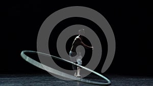 Muscular circus artist perform Cyr Wheel on a black background. Concept of willpower, motivation and passion