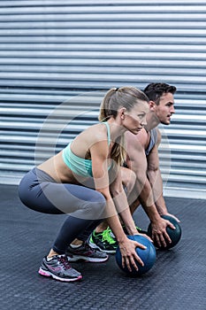 Muscular couple doing ball exercise