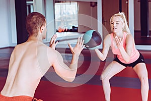 Muscular couple doing exercises with ball in modern gym