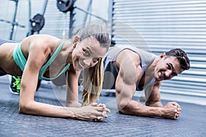 Muscular couple doing planking exercises