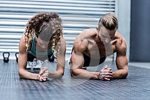 Muscular couple doing planking exercises photo