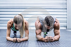 Muscular couple doing planking exercises photo