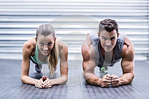 Muscular couple doing planking exercises photo