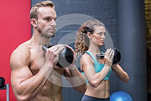 Muscular couple exercising with kettlebells