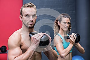 Muscular couple exercising with kettlebells