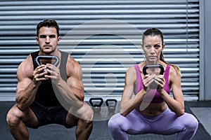 Muscular couple exercising with kettlebells