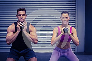 Muscular couple exercising with kettlebells