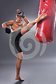 Muscular Fighter Practicing Some Kicks with Punching Bag