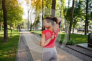 Muscular fit athlete, middle aged confident sportswoman raising arms up, stretching out and warming up her body before morning jog