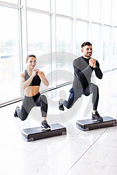 Muscular fitness couple doing jumping squats in crossfit gym