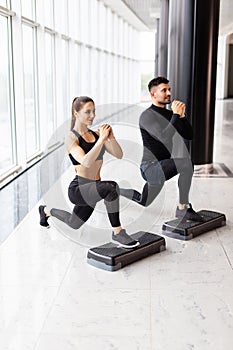 Muscular fitness couple doing jumping squats in crossfit gym