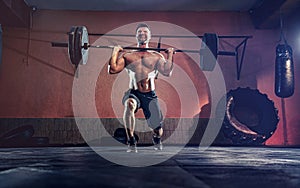 Muscular fitness man doing barbell lunges in his garage, selfiso