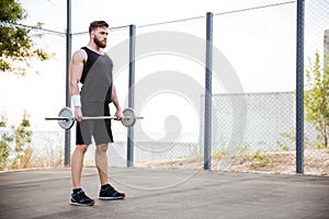 Muscular fitness man doing heavy exercise using barbell