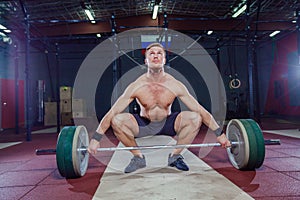 Muscular fitness man preparing to deadlift a barbell over his head in modern fitness center.Functional training.Snatch