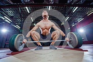 Muscular fitness man preparing to deadlift a barbell over his head in modern fitness center.Functional training.Snatch