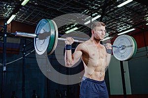 Muscular fitness man preparing to deadlift a barbell over his head in modern fitness center.Functional training.Snatch