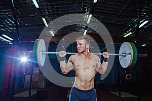 Muscular fitness man preparing to deadlift a barbell over his head in modern fitness center.Functional training.Snatch