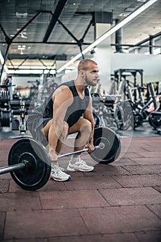 Muscular fitness man preparing to deadlift a barbell over his head in modern fitness center.Functional training.Snatch exercise