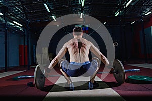 Muscular fitness man preparing to deadlift a barbell over his head in modern fitness center.Functional training.Snatch