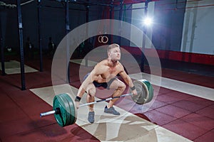 Muscular fitness man preparing to deadlift a barbell over his head in modern fitness center.Functional training.Snatch