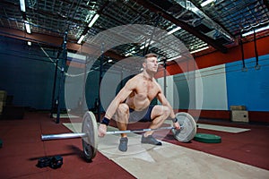 Muscular fitness man preparing to deadlift a barbell over his head in modern fitness center.Functional training.Snatch