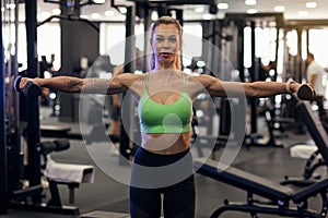 Muscular fitness woman athlete doing heavy weight exercise for shoulders with dumbbells in the gym