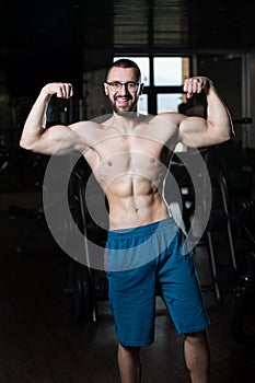 Muscular Geek Man Flexing Muscles In Gym