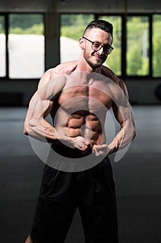 Muscular Geek Man Flexing Muscles In Gym