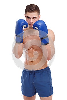 A muscular guy in boxing gloves is standing in a fighting stance close-up on a white isolated background. Front view