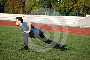 Muscular guy doing stretching after jogging