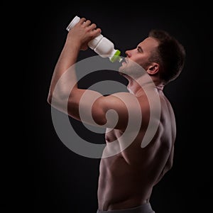 Muscular guy drinking water after training