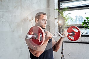 Muscular guy lifting barbell in studio room with spotlights