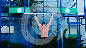 Muscular guy pull up on a crossbar at the sports ground