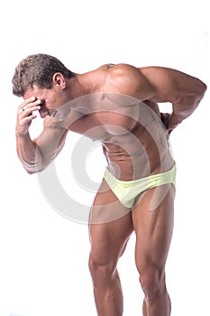 Muscular handsome man holding his back in pain