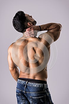 Muscular handsome man holding his neck in pain