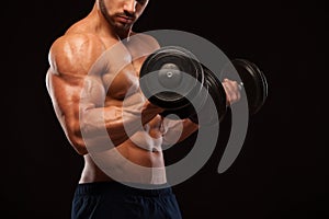 Muscular handsome man is training with dumbbells in gym. isolated on black background with copyspace