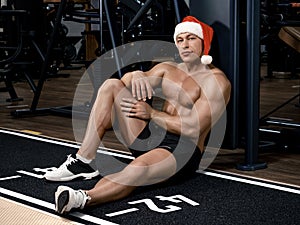 Muscular handsome sexy bodybuilder Santa Claus resting after training