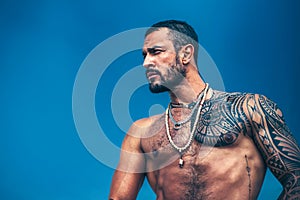 Muscular latin lover. Latin Man with muscular body looks seriously. Handsome brutal man on blue sky background. Portrait