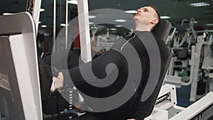 Muscular male athlete doing leg press exercise, working out at fitness club