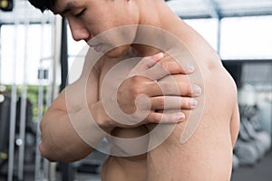 Muscular male having pain on shoulder in gym. young man injure