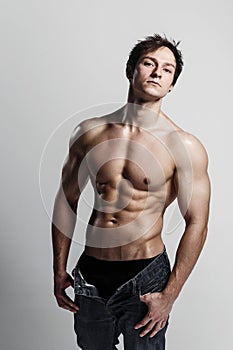 Muscular male model bodybuilder with unbuttoned jeans. Studio sh