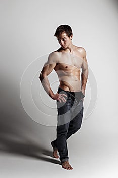 Muscular male model bodybuilder with unbuttoned jeans. Studio sh