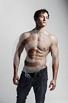 Muscular male model bodybuilder with unbuttoned jeans. Studio sh photo