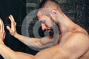 Muscular male taking a shower, details of man in rainshower