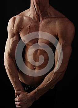 Muscular male torso isolated on black background.