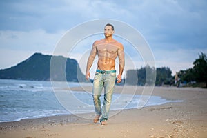 Muscular male walking along a beach photo