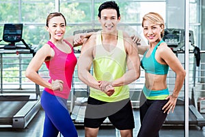 Muscular man amongst two sportive women striking pose