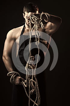 Muscular man in apron with rope